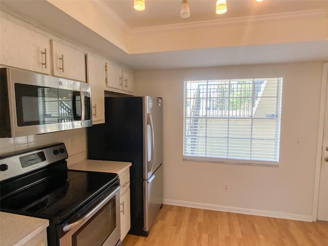 kitchen featuring ornamental molding, baseboards, light countertops, light wood-style flooring, and appliances with stainless steel finishes