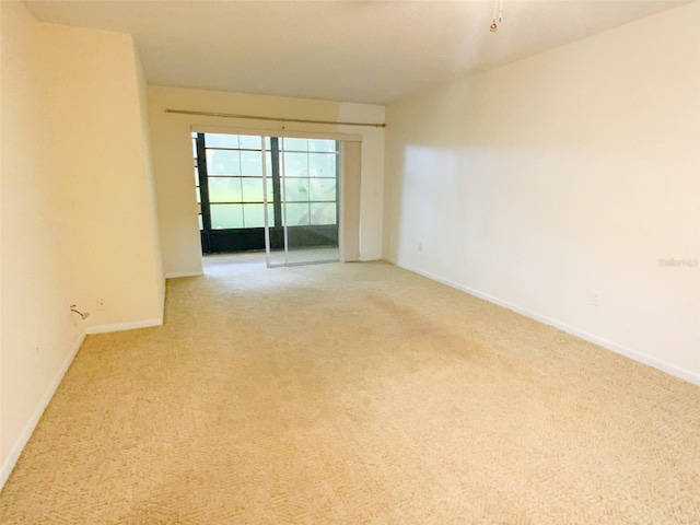 spare room featuring baseboards and light carpet