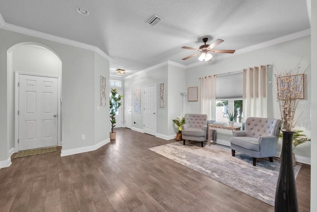sitting room with arched walkways, ceiling fan, wood finished floors, baseboards, and ornamental molding