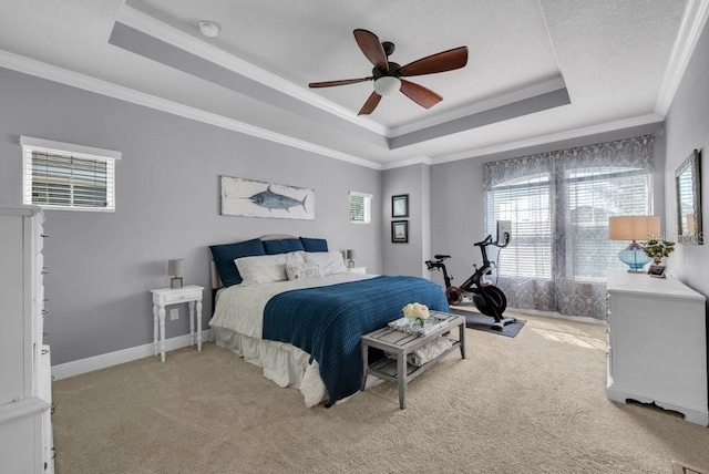 bedroom featuring a tray ceiling, crown molding, light carpet, and ceiling fan