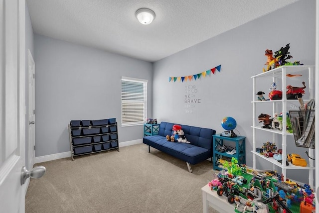 recreation room with carpet, a textured ceiling, and baseboards