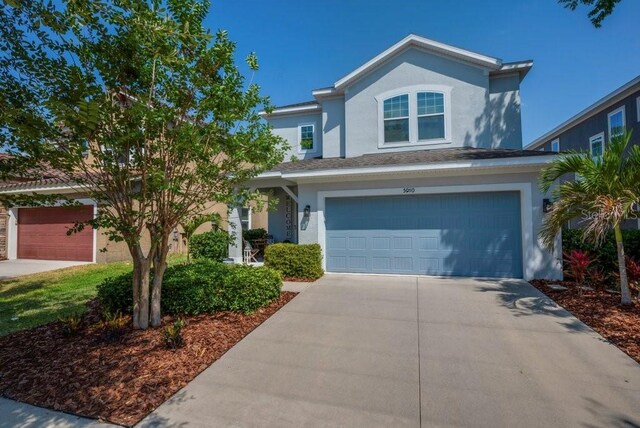 traditional-style home featuring stucco siding, a garage, and concrete driveway