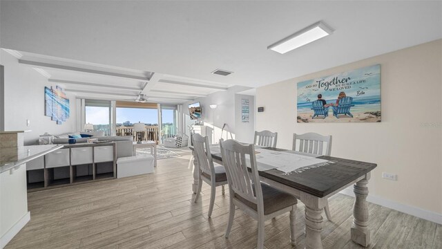 dining area featuring light wood-style floors, baseboards, beamed ceiling, and coffered ceiling