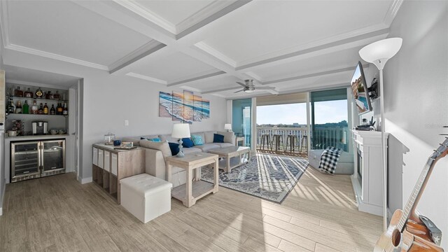 living room featuring a ceiling fan, beamed ceiling, a bar, beverage cooler, and light wood-style floors