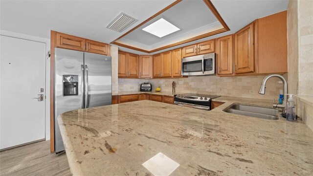 kitchen with light stone countertops, appliances with stainless steel finishes, a sink, backsplash, and visible vents