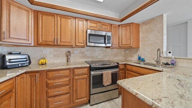 kitchen featuring brown cabinetry, crown molding, appliances with stainless steel finishes, tasteful backsplash, and a sink