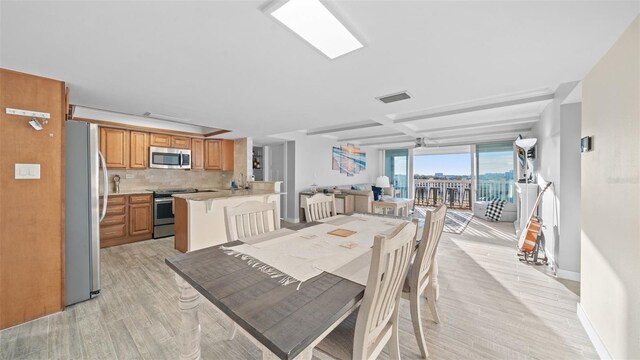 dining area featuring light wood-type flooring, baseboards, and visible vents