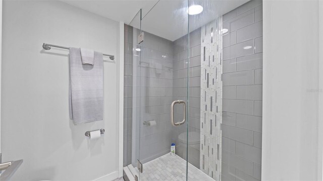 bathroom featuring baseboards, a stall shower, and toilet
