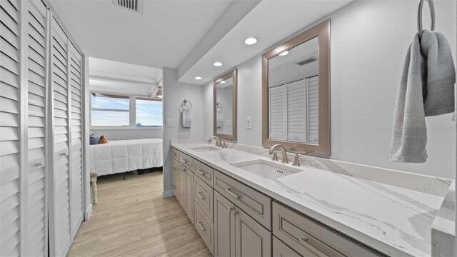 ensuite bathroom with recessed lighting, a sink, wood finished floors, and visible vents