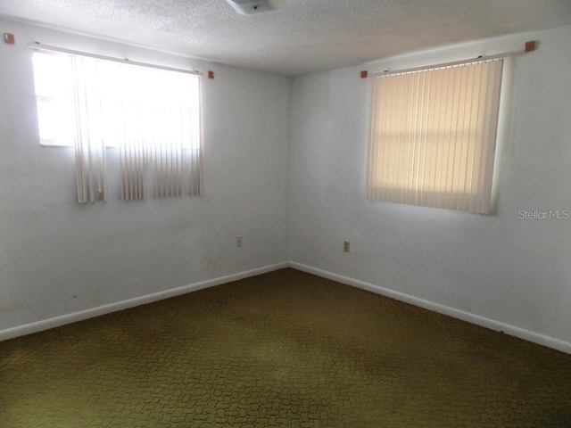 spare room featuring baseboards, a textured ceiling, and carpet floors