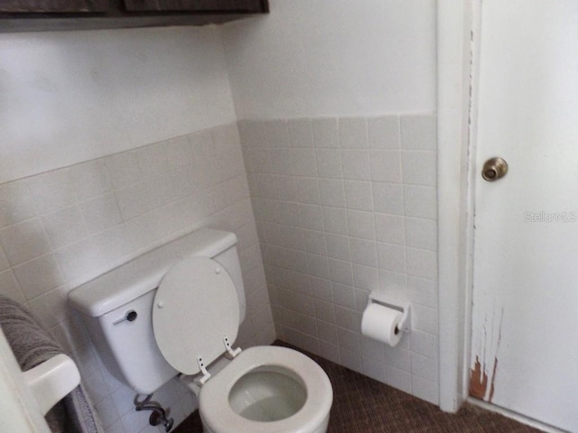 bathroom featuring toilet and tile walls