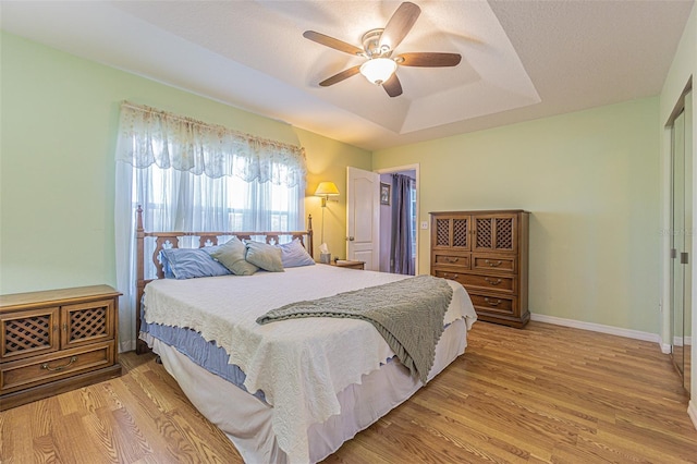 11311 Corey Pavin Ln, San Antonio, FL 33576 - bedroom featuring a tray ceiling, wood finished floors, and a ceiling fan
