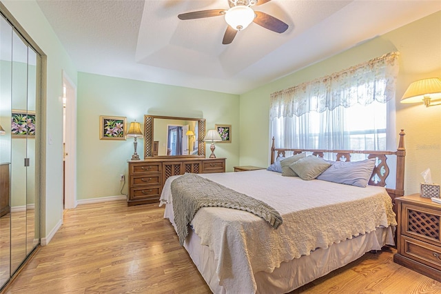 11311 Corey Pavin Ln, San Antonio, FL 33576 - bedroom featuring light wood-style floors, a tray ceiling, ceiling fan, and a closet