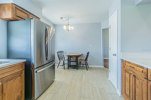 11311 Corey Pavin Ln, San Antonio, FL 33576 - kitchen with freestanding refrigerator, brown cabinets, a chandelier, and light countertops