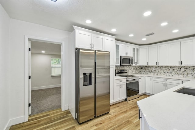 10011 N Annette Ave, Tampa, FL 33612 - kitchen featuring appliances with stainless steel finishes, light wood finished floors, backsplash, light countertops, and white cabinets