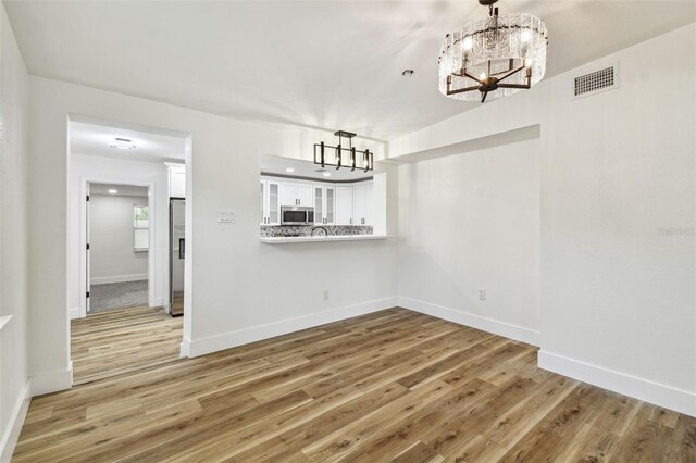 10011 N Annette Ave, Tampa, FL 33612 - unfurnished dining area with a chandelier and light wood-style flooring