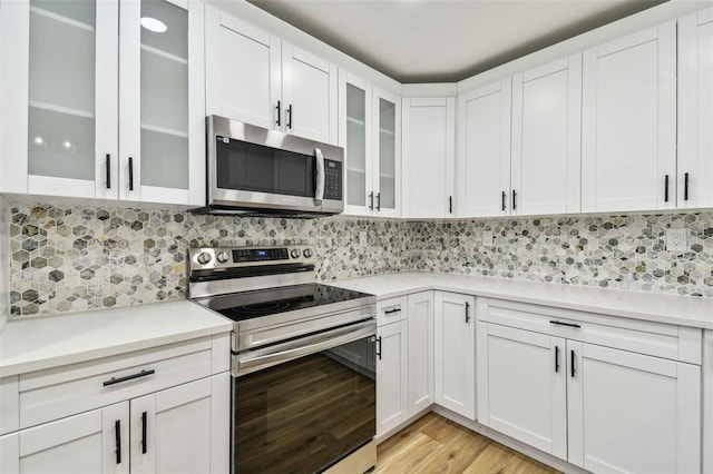 10011 N Annette Ave, Tampa, FL 33612 - kitchen featuring stainless steel appliances, light wood finished floors, light countertops, white cabinets, and glass insert cabinets