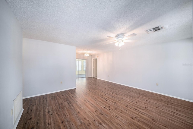 spare room with a textured ceiling, ceiling fan, wood finished floors, and visible vents