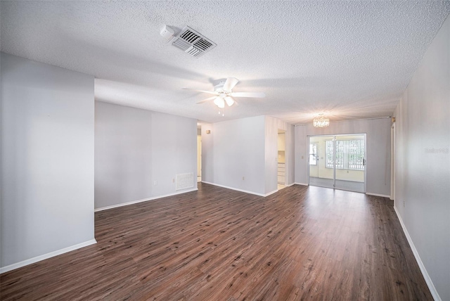 empty room with visible vents, a textured ceiling, dark wood-type flooring, and ceiling fan with notable chandelier