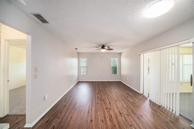 interior space featuring ceiling fan, dark wood-style floors, a textured ceiling, and visible vents