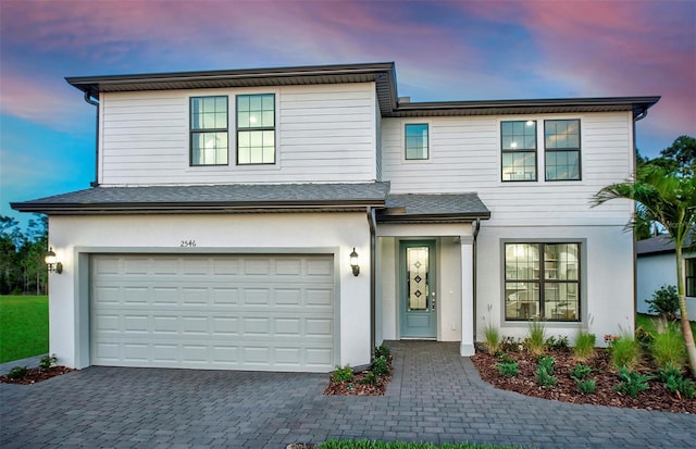 5953 Bluestar Ct, Lakewood Ranch, FL 34211 - view of front facade featuring stucco siding, decorative driveway, a shingled roof, and a garage