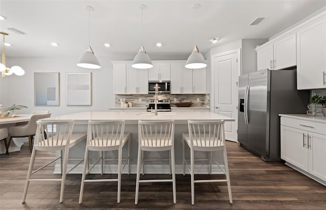 5953 Bluestar Ct, Lakewood Ranch, FL 34211 - kitchen featuring tasteful backsplash, light countertops, an island with sink, stainless steel appliances, and dark wood-type flooring