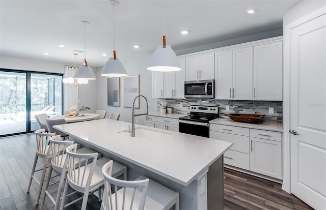 5953 Bluestar Ct, Lakewood Ranch, FL 34211 - kitchen with decorative backsplash, white cabinets, a sink, dark wood finished floors, and stainless steel appliances