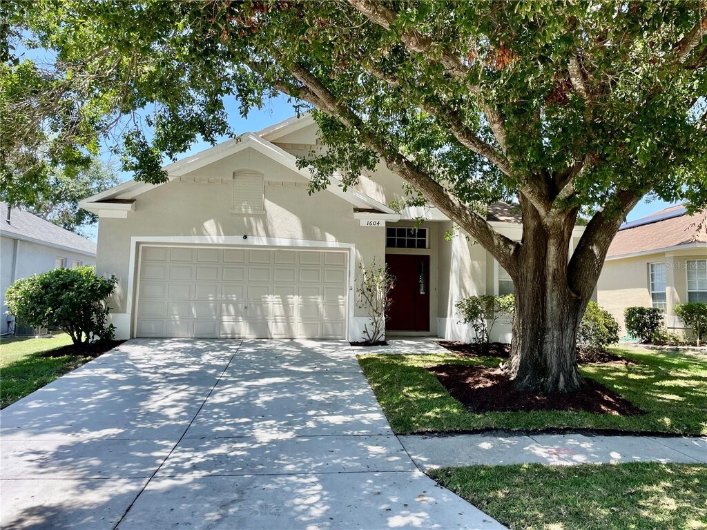 ranch-style home with an attached garage, concrete driveway, and stucco siding
