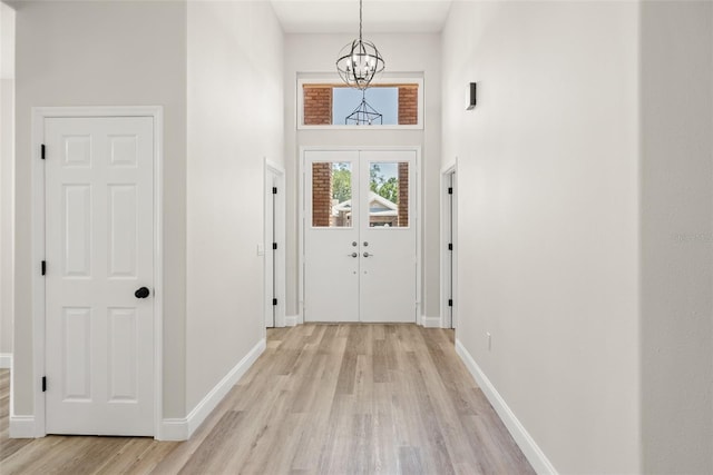 4317 74th Ave E, Sarasota, FL 34243 - doorway to outside featuring an inviting chandelier, baseboards, light wood finished floors, and a towering ceiling
