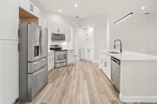 4317 74th Ave E, Sarasota, FL 34243 - kitchen with light wood-type flooring, a sink, tasteful backsplash, and stainless steel appliances