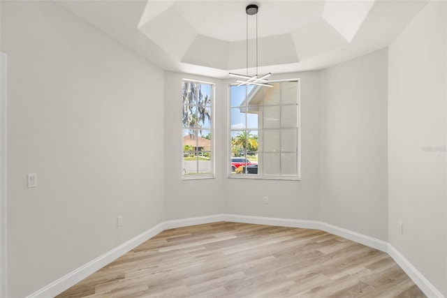 4317 74th Ave E, Sarasota, FL 34243 - unfurnished dining area with a raised ceiling, baseboards, light wood-type flooring, and a chandelier