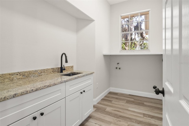4317 74th Ave E, Sarasota, FL 34243 - laundry area with a sink, baseboards, light wood-style floors, and cabinet space