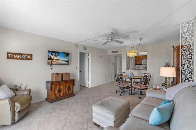 living room with light tile patterned flooring, a textured ceiling, a ceiling fan, and visible vents