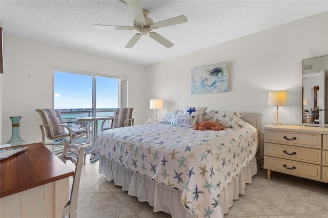 bedroom with light tile patterned floors, a ceiling fan, and a textured ceiling