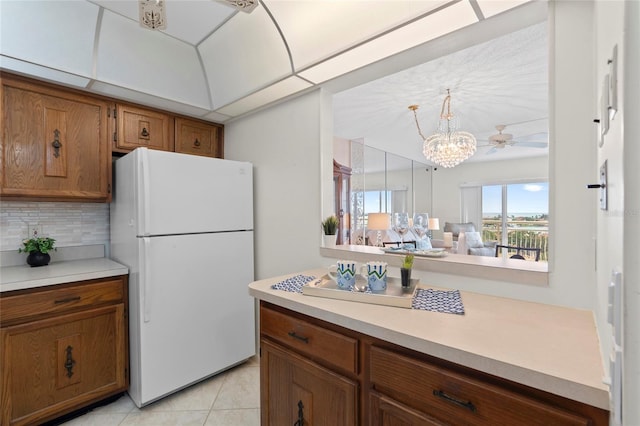 kitchen featuring freestanding refrigerator, light countertops, decorative backsplash, and brown cabinets