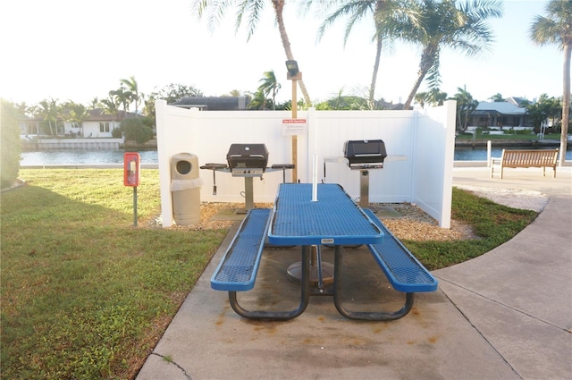 exterior space featuring a lawn, a water view, fence, and outdoor dining space