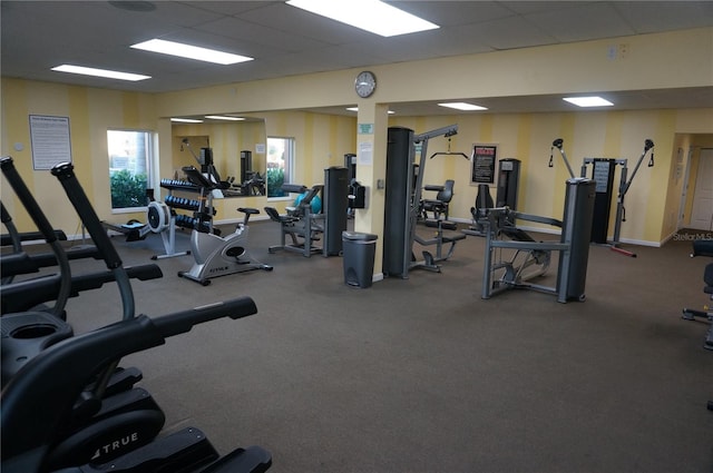 exercise room featuring baseboards and a drop ceiling