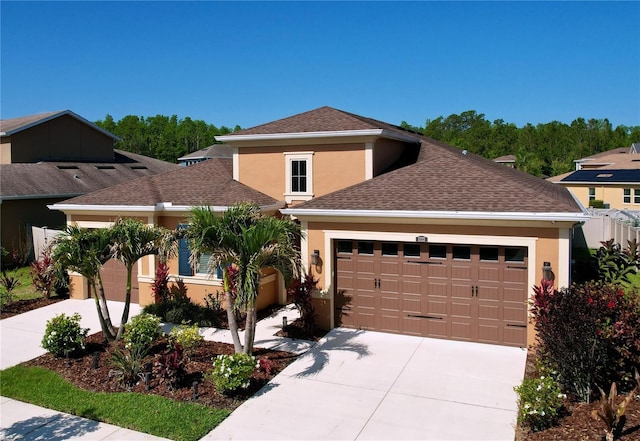 view of front of house with concrete driveway, an attached garage, a shingled roof, and stucco siding