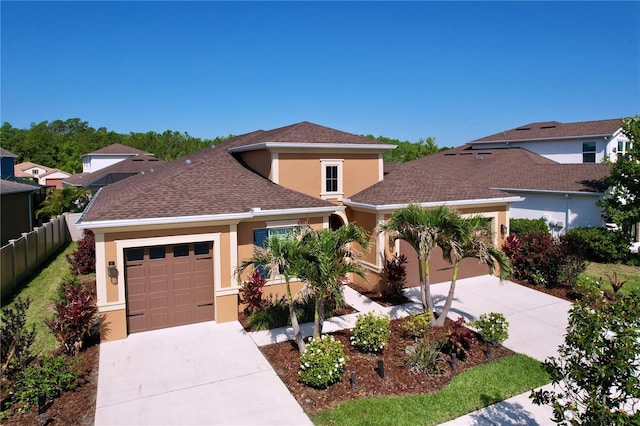 view of front facade featuring a garage, stucco siding, fence, and concrete driveway