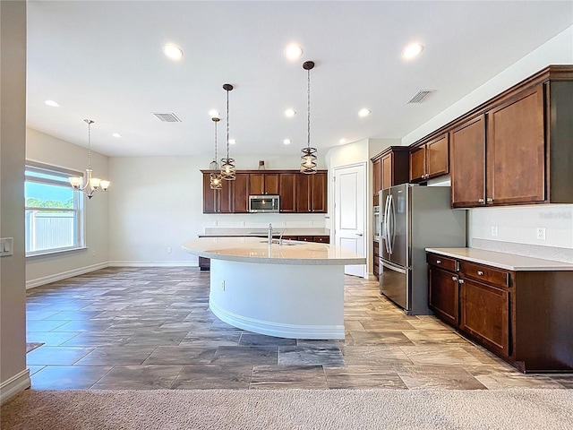kitchen with a notable chandelier, a sink, light countertops, stainless steel appliances, and visible vents