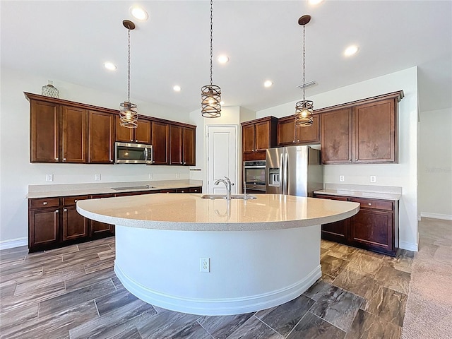 kitchen featuring a sink, an island with sink, stainless steel appliances, baseboards, and visible vents