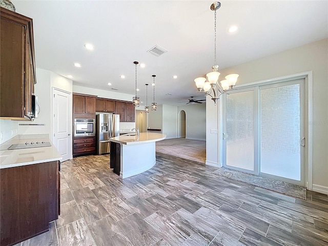 kitchen featuring visible vents, a sink, ceiling fan with notable chandelier, open floor plan, and stainless steel appliances
