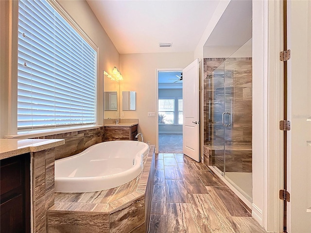 full bathroom featuring visible vents, vanity, a garden tub, ceiling fan, and a shower stall