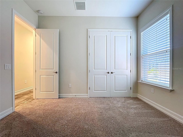 unfurnished bedroom with a closet, baseboards, carpet flooring, and visible vents