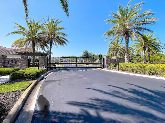 view of street with a gate, a gated entry, and curbs