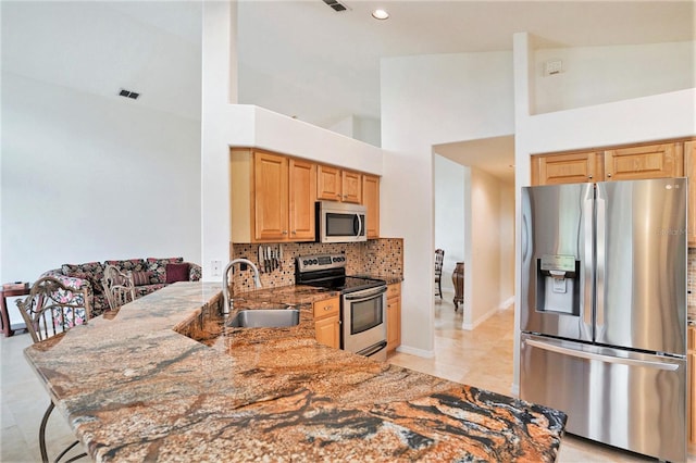 3023 Bent Creek Dr, Valrico, FL 33596 - kitchen featuring appliances with stainless steel finishes, light stone countertops, backsplash, a peninsula, and a towering ceiling