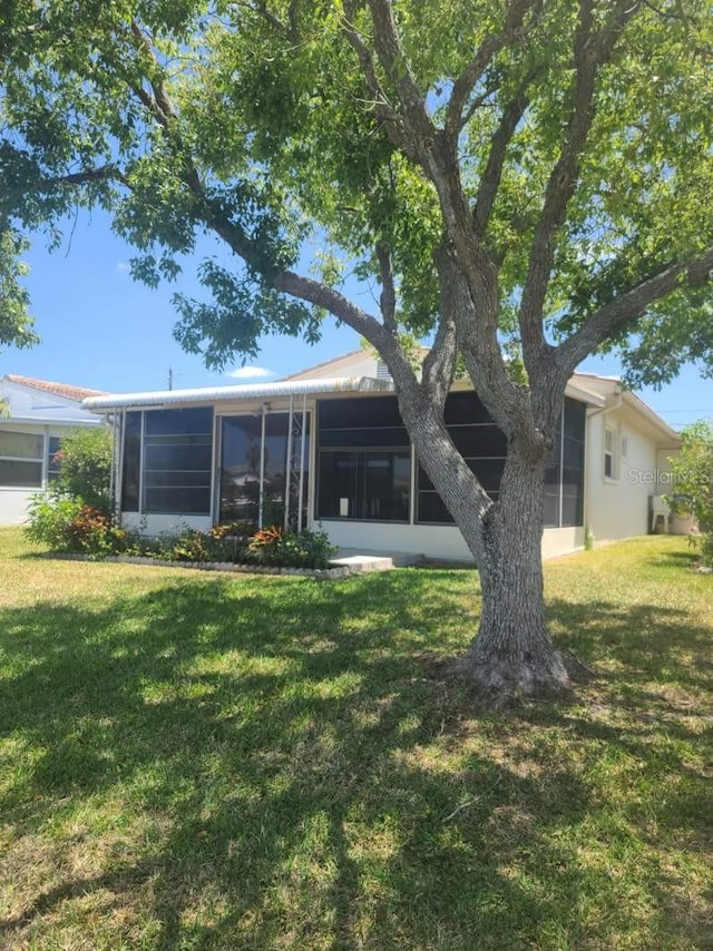 5105 Bonito Dr, New Port Richey, FL 34652 - back of house featuring a lawn and a sunroom