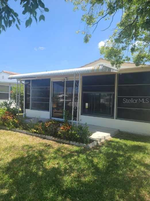 5105 Bonito Dr, New Port Richey, FL 34652 - back of house featuring a yard and a sunroom