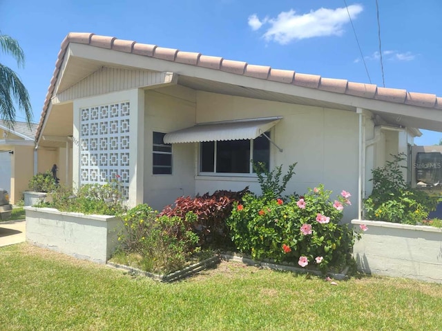 5105 Bonito Dr, New Port Richey, FL 34652 - view of property exterior featuring stucco siding, a yard, and a tile roof