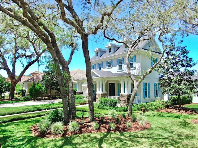 victorian-style house featuring stucco siding, a porch, and a front lawn